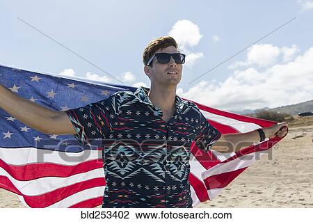 Caucasian man holding American flag on beach View Large Photo Image Stock Image - Caucasian man holding American flag on beach. Fotosearch