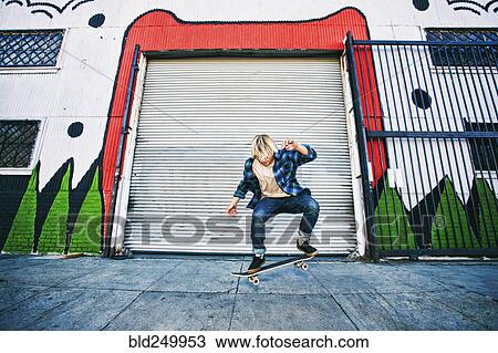 Stock Image - Caucasian man jumping on skateboard. Fotosearch