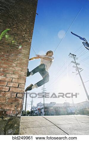 Caucasian man jumping on urban wall View Large Photo Image Stock Image - Caucasian man jumping on urban wall. Fotosearch