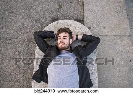 Caucasian man laying on concrete smoking cigarette View Large Photo Image Stock Photo - Caucasian man laying on concrete smoking cigarette. Fotosearch