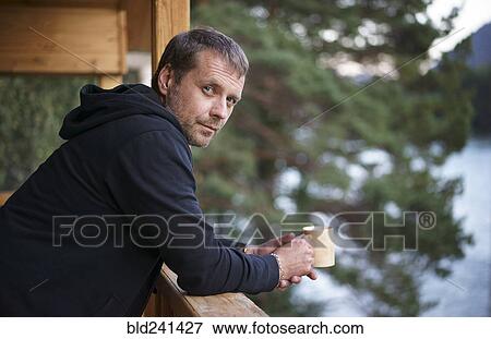 Caucasian man leaning on railing drinking coffee View Large Photo Image Stock Photo - Caucasian man leaning on railing drinking coffee. Fotosearch