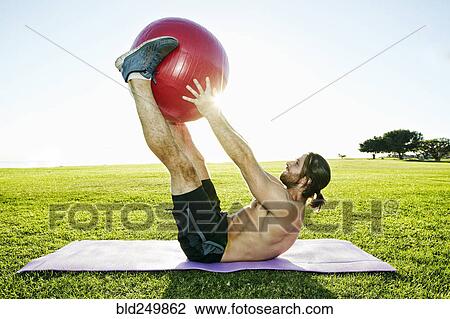 Caucasian man lifting fitness ball with legs in sunny field View Large Photo Image Stock Image - Caucasian man lifting fitness ball with legs in sunny field. Fotosearch