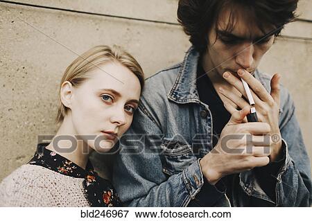 Stock Photo - Caucasian man lighting cigarette near woman. Fotosearch