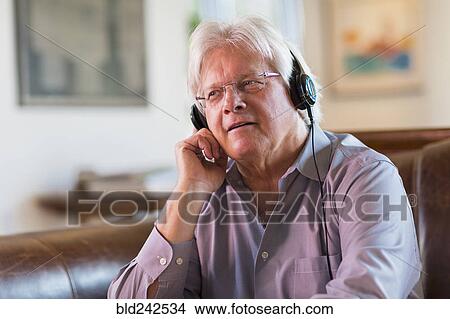 Picture - Caucasian man listening to headphones. Fotosearch