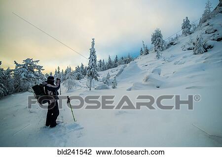 Stock Image - Caucasian man photographing snowy mountain. Fotosearch