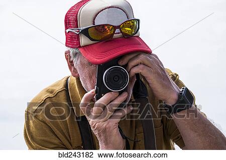 Stock Image - Caucasian man photographing with camera. Fotosearch