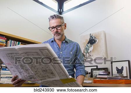 Caucasian man reading blueprint in office View Large Photo Image Stock Image - Caucasian man reading blueprint in office. Fotosearch