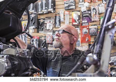 Caucasian man repairing motorcycle View Large Photo Image Picture - Caucasian man repairing motorcycle. Fotosearch