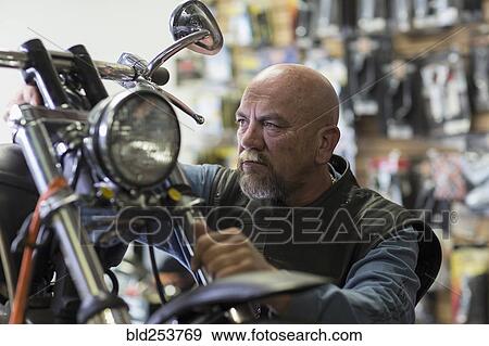 Stock Photo - Caucasian man repairing motorcycle. Fotosearch
