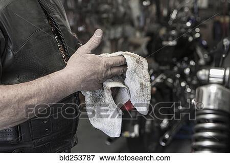 Caucasian man repairing motorcycle wiping hands View Large Photo Image Stock Photo - Caucasian man repairing motorcycle wiping hands. Fotosearch