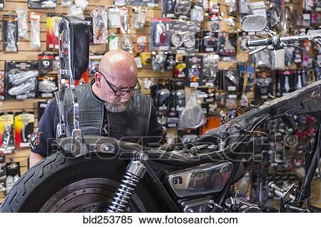 Stock Photography - Caucasian man repairing motorcycle. Fotosearch
