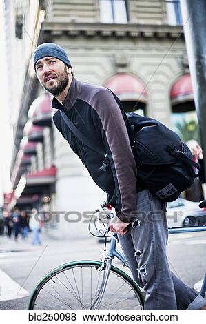 Caucasian man riding bicycle in city View Large Photo Image Stock Photo - Caucasian man riding bicycle in city. Fotosearch