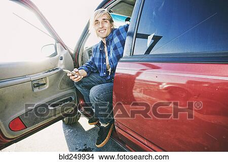 Caucasian man sitting in car texting on cell phone View Large Photo Image Picture - Caucasian man sitting in car texting on cell phone. Fotosearch