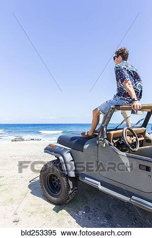 Caucasian man sitting in windshield of convertible car on beach View Large Photo Image Stock Photography - Caucasian man sitting in windshield of convertible car on beach. Fotosearch