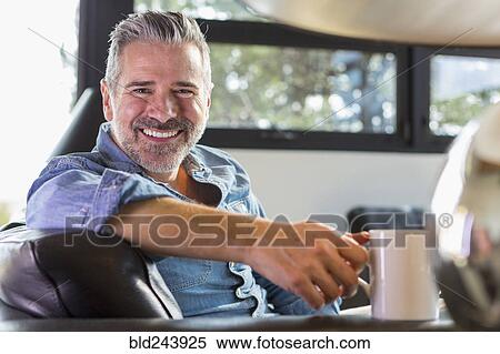 Caucasian man sitting on sofa and drinking coffee View Large Photo Image Stock Photography - Caucasian man sitting on sofa and drinking coffee. Fotosearch