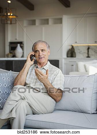 Caucasian man sitting on sofa talking on cell phone View Large Photo Image Stock Photograph - Caucasian man sitting on sofa talking on cell phone. Fotosearch