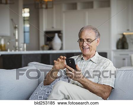 Caucasian man sitting on sofa texting on cell phone View Large Photo Image Stock Photography - Caucasian man sitting on sofa texting on cell phone. Fotosearch