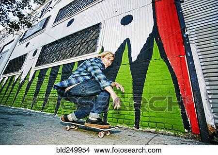 Caucasian man skateboarding on urban sidewalk View Large Photo Image Picture - Caucasian man skateboarding on urban sidewalk. Fotosearch