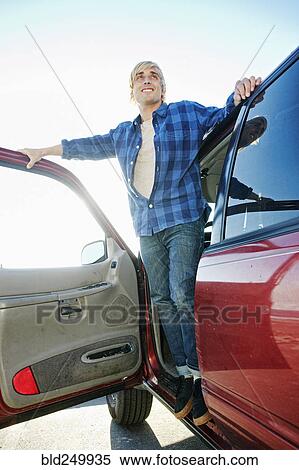 Stock Photography - Caucasian man standing in car door. Fotosearch