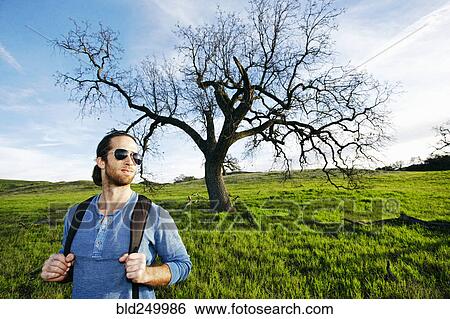 Caucasian man standing in field near tree View Large Photo Image Stock Photograph - Caucasian man standing in field near tree. Fotosearch