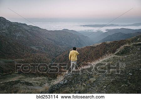 Picture - Caucasian man standing in remote mountain landscape. Fotosearch