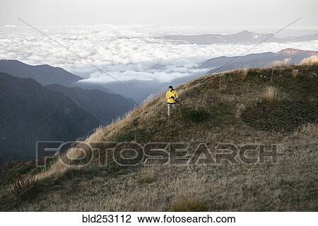Stock Image - Caucasian man standing in remote mountain landscape. Fotosearch