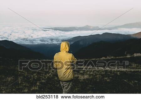 Stock Photo - Caucasian man standing in remote mountain landscape. Fotosearch