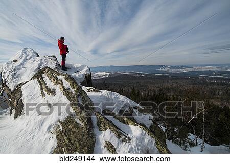 Picture - Caucasian man standing in snow admiring scenic view of forest. Fotosearch