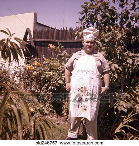 Stock Photo - Caucasian man standing in yard wearing chef hat and apron. Fotosearch