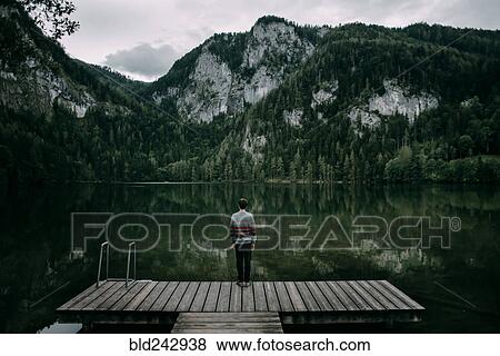 Caucasian man standing on dock admiring scenic view of mountain View Large Photo Image Stock Photo - Caucasian man standing on dock admiring scenic view of mountain. Fotosearch