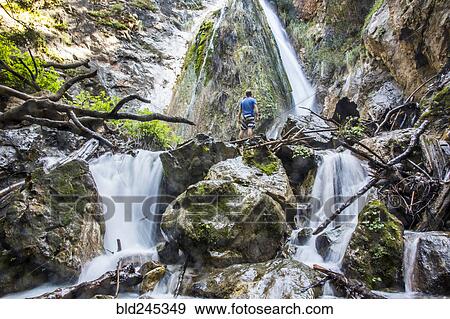 Caucasian man standing on rocks watching waterfall View Large Photo Image Stock Photo - Caucasian man standing on rocks watching waterfall. Fotosearch