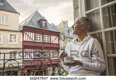 Caucasian man stirring coffee on balcony in city View Large Photo Image Stock Photo - Caucasian man stirring coffee on balcony in city. Fotosearch