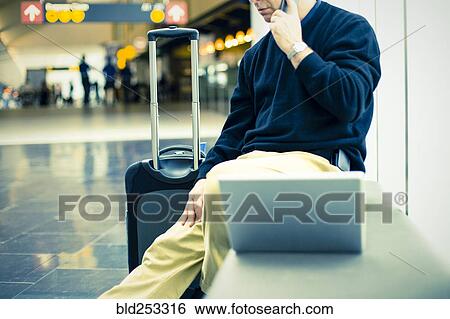 Caucasian man talking on cell phone at airport View Large Photo Image Stock Photograph - Caucasian man talking on cell phone at airport. Fotosearch