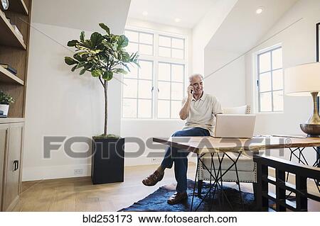 Caucasian man talking on cell phone in home office View Large Photo Image Stock Image - Caucasian man talking on cell phone in home office. Fotosearch
