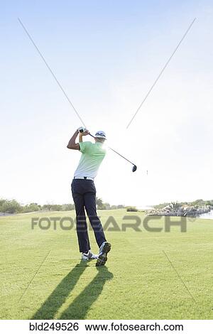 Stock Photograph - Caucasian man teeing off on golf course. Fotosearch
