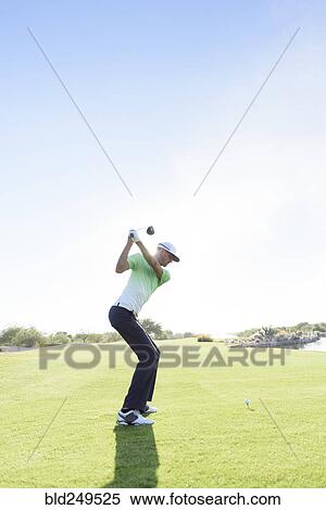 Stock Photography - Caucasian man teeing off on golf course. Fotosearch