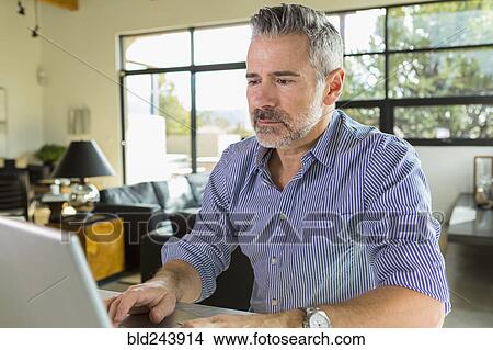 Picture - Caucasian man using laptop on table. Fotosearch