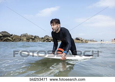 Caucasian man wading in ocean holding surfboard View Large Photo Image Stock Image - Caucasian man wading in ocean holding surfboard. Fotosearch