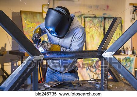 Stock Photography - Caucasian man welding metal sculpture. Fotosearch
