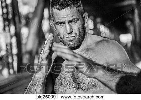 Stock Image - Caucasian man with bare chest with hands raised. Fotosearch