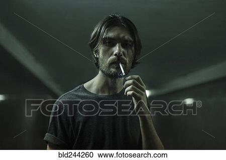 Stock Image - Caucasian man with beard smoking cigarette. Fotosearch