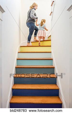 Stock Image - Caucasian mother and daughter climbing multicolor staircase. Fotosearch