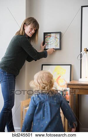 Caucasian mother and daughter hanging painting on wall View Large Photo Image Stock Image - Caucasian mother and daughter hanging painting on wall. Fotosearch
