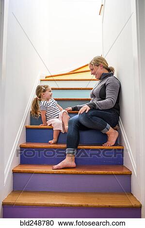 Stock Image - Caucasian mother and daughter laughing on multicolor staircase. Fotosearch