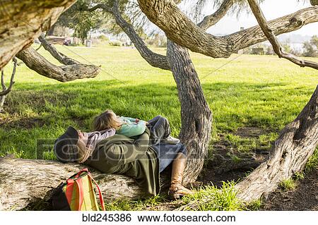 Stock Photograph - Caucasian mother and daughter laying on tree branch. Fotosearch