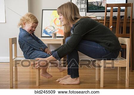 Stock Photo - Caucasian mother and daughter sitting on small chairs in home office. Fotosearch