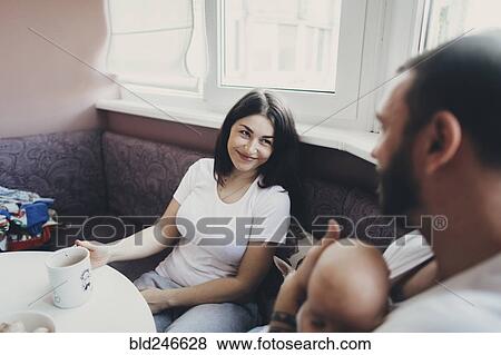 Stock Photo - Caucasian mother and daughter sitting at table with baby son. Fotosearch