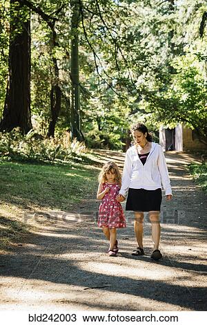 Caucasian mother and daughter walking on path in park View Large Photo Image Stock Image - Caucasian mother and daughter walking on path in park. Fotosearch