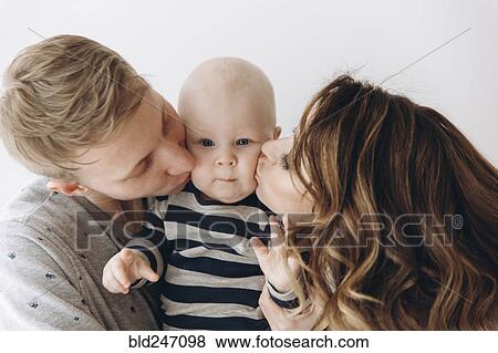 Stock Photo - Caucasian mother and father kissing baby son on cheek. Fotosearch