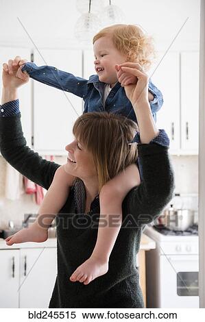 Caucasian mother carrying daughter on shoulders in kitchen View Large Photo Image Stock Photography - Caucasian mother carrying daughter on shoulders in kitchen. Fotosearch